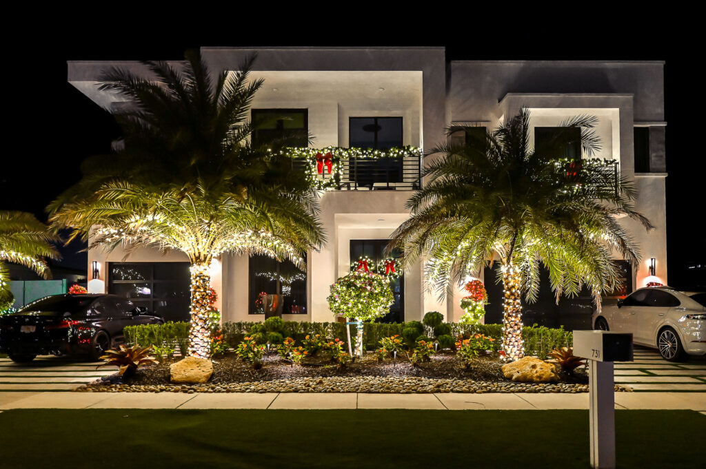 Clean, modern house with multiple palm trees and bushes professionally wrapped with high-end holiday lighting installation in South Florida