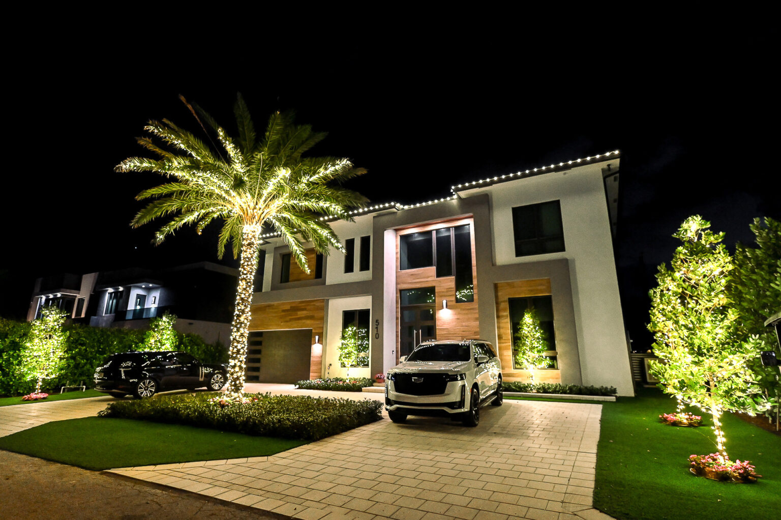 Beautiful and modern home in Boca Raton with the most professional-looking holiday lighting installation on the roofline as well as a palm tree in the front yard