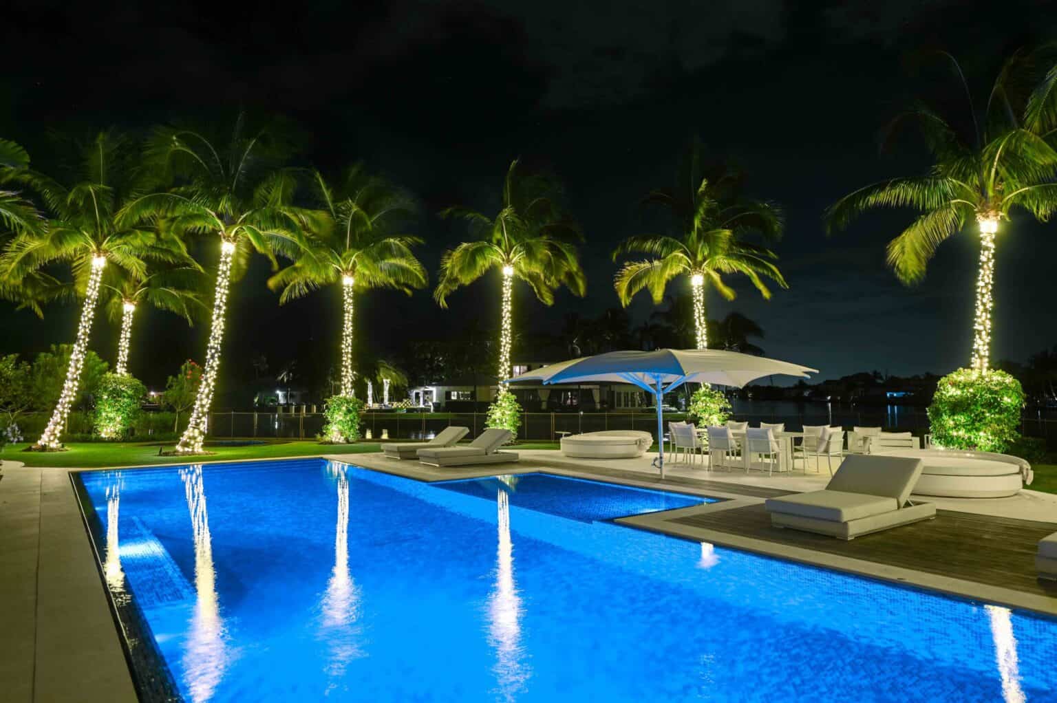 High-end holiday lights installed in multiple palm trees in the backyard of a pool-side are of a big, wealthy home in Gulf Stream, FL.